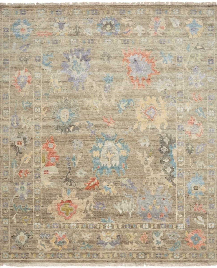 traditional area rug with a weathered walnut taupe field and muted floral patterns in coral, azure blue, and soft gold.